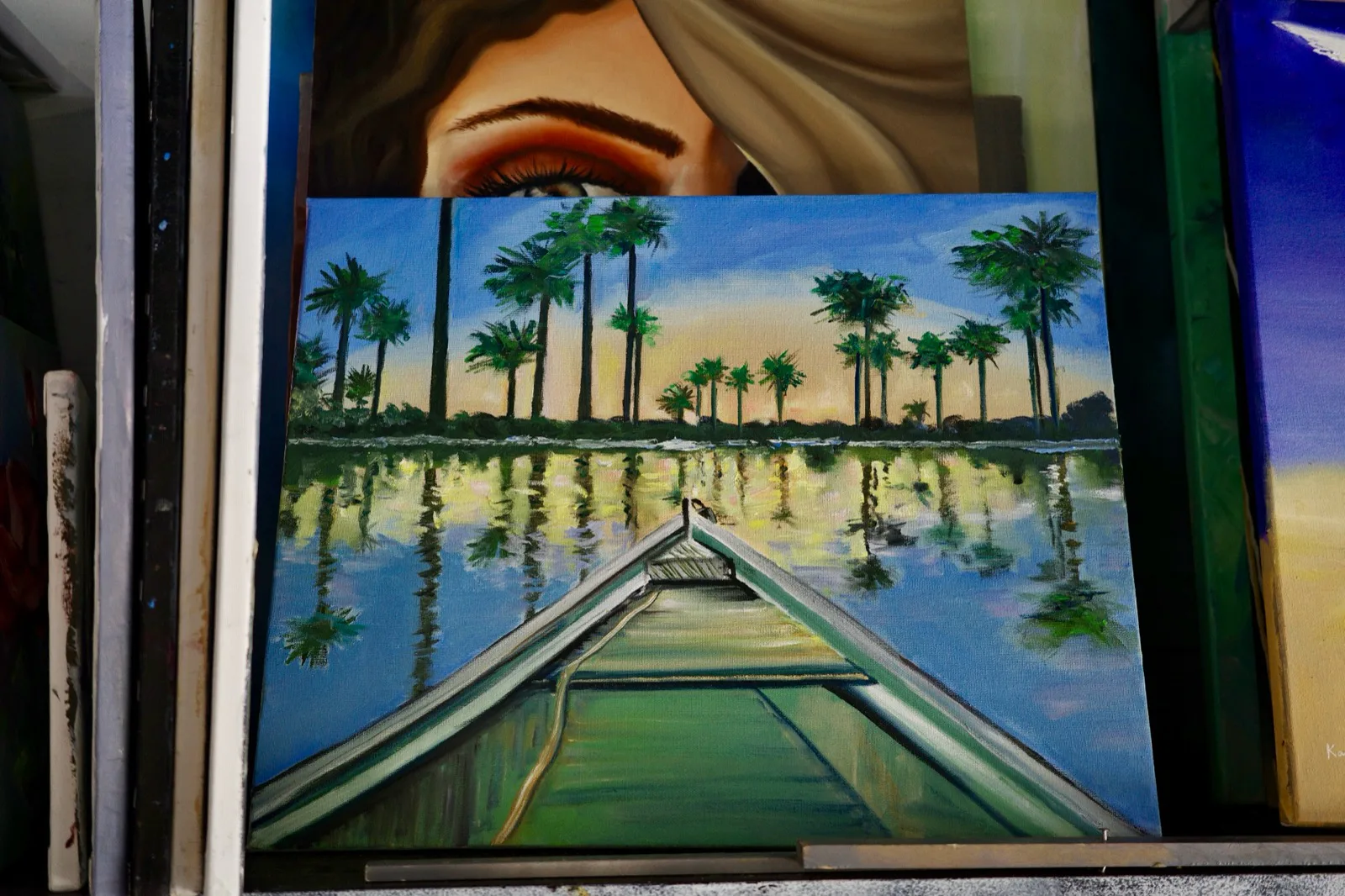 Oil painting from the bow of a boat facing palm trees reflected in still water at sunset.